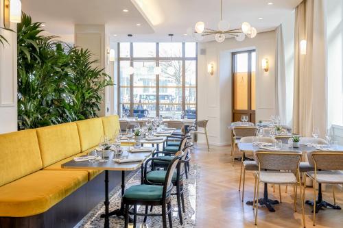 斯特拉斯堡Hotel des Vosges BW Premier Collection的一间带桌椅和黄色沙发的餐厅