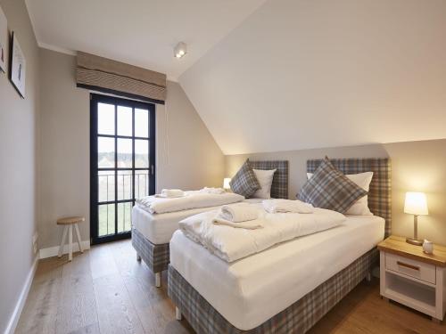 德兰斯克Reetland am Meer - Luxus Reetdachvilla mit 3 Schlafzimmern, Sauna und Kamin F12的一间卧室设有两张床和窗户。