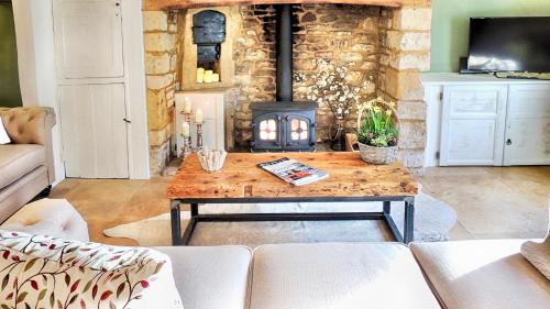 莫顿因马什Magnolia Cottage的客厅配有木桌和壁炉