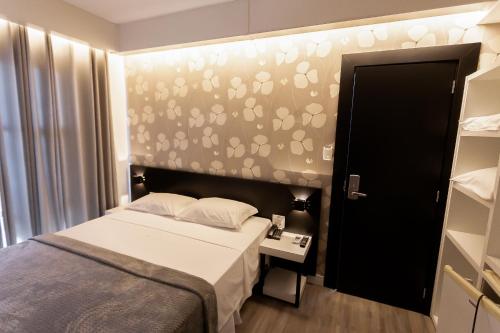 阿拉沙Hotel Cidade Araxá的一间小卧室,配有一张床和一张带足迹的墙壁