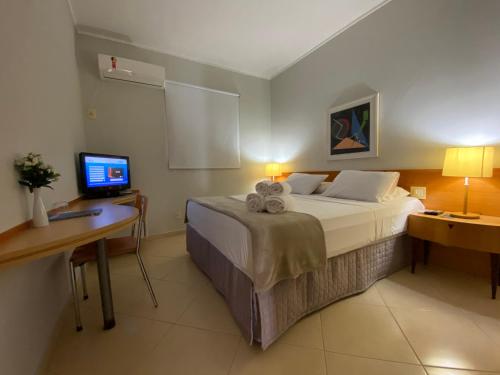 里贝朗普雷托佳纳达酒店的一间卧室配有一张床和一张带电脑的书桌
