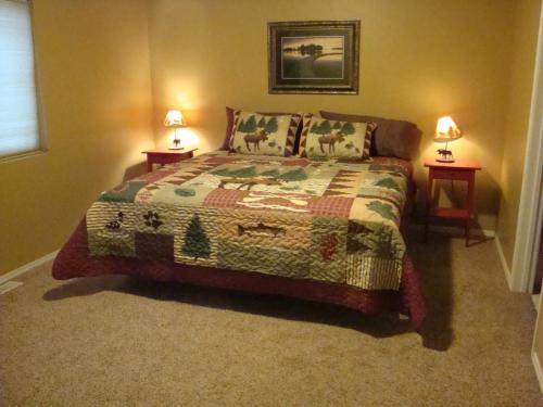西黄石Geyser Mountain Home的一间卧室配有一张床,两台桌子上放着两盏灯