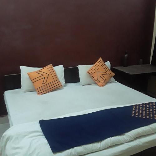 瓜廖尔shri bake bihari guest house的一张带橙色和蓝色枕头的床