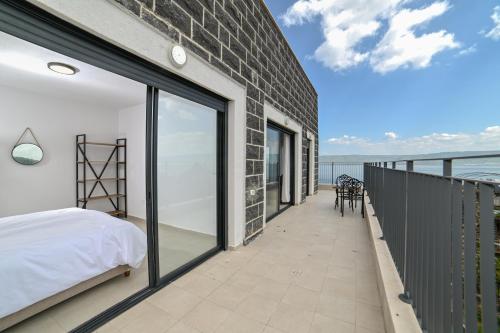 提比里亚Europa Residence的一间带一张床的卧室,位于一个海景阳台上