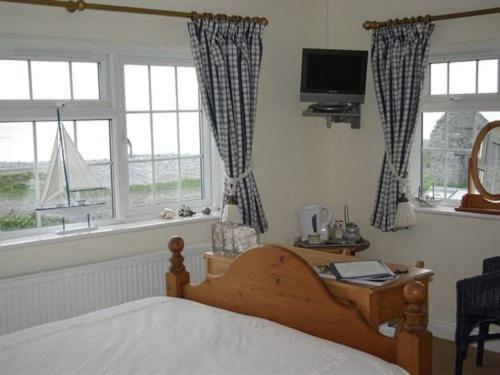 Gileston1-Bed Cottage on Coastal Pathway in South Wales的一间卧室设有一张床、一台电视和窗户。