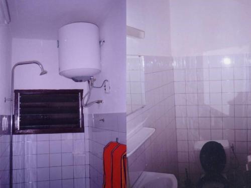 洛美玛丽安托瓦内特洛美酒店的浴室配有卫生间和墙上的灯。
