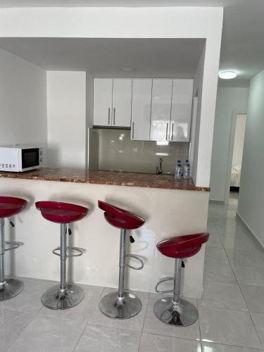 罗萨里奥港Apartamentos Tamasite的厨房在厨房柜台上配有红色凳子