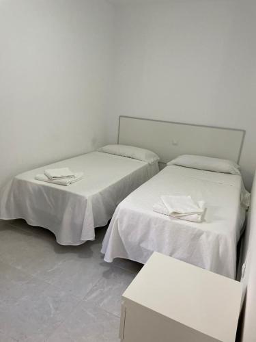 罗萨里奥港Apartamentos Tamasite的白色墙壁客房的两张床