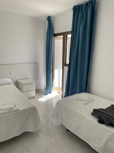 罗萨里奥港Apartamentos Tamasite的配有蓝色窗帘的客房内的两张床