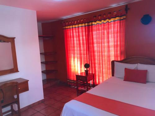 瓦哈卡市拉卡斯卡达酒店的一间卧室配有床和红色窗帘的窗户