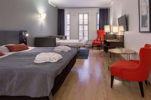 赫尔辛基斯堪迪克码头大酒店的酒店客房,设有两张床和一张红色椅子