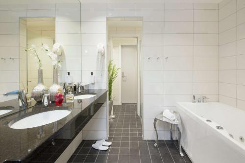 埃尔沃吕姆Thon Partner Elgstua Hotel的白色的浴室设有两个水槽、一个浴缸和一个浴缸。