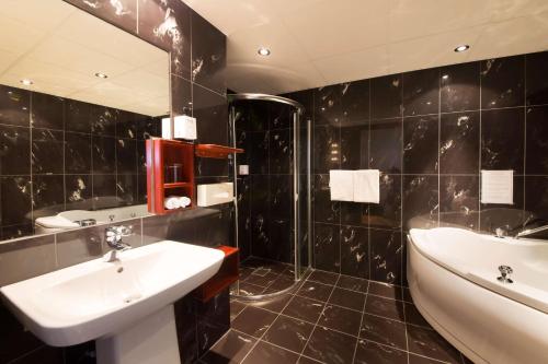 格里姆斯塔Clarion Collection Hotel Grimstad的黑色瓷砖浴室设有水槽和浴缸
