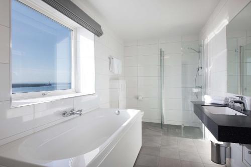 斯沃尔韦尔Scandic Vestfjord Lofoten的白色的浴室设有浴缸和水槽。