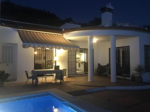 阿里纳斯Belvilla by OYO Villa in Arenas with Private Pool的天井配有桌子,晚上设有游泳池