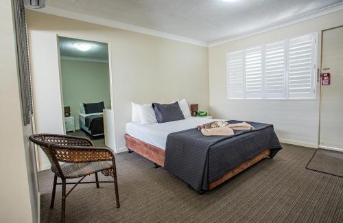 黄金海岸纯品康纳汽车旅馆的卧室配有床、椅子和窗户。