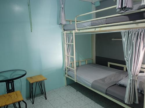 清迈i-微笑旅舍的一间卧室配有双层床、桌子和凳子