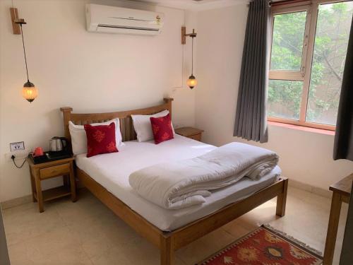 阿格拉胡子阿格拉旅舍的一间卧室配有带白色床单和红色枕头的床。