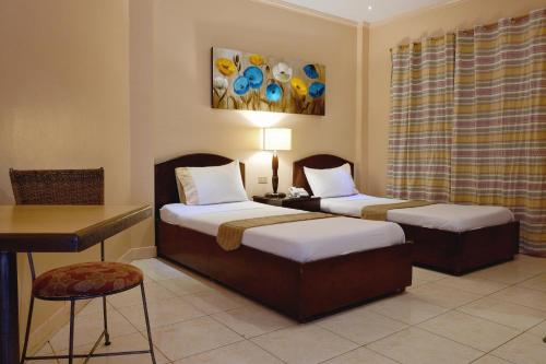 宿务攀升宫酒店的客房设有两张床、一张桌子和一张书桌。