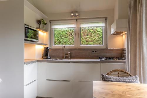 斯霍尔Vakantiewoning met privé sauna的厨房配有白色橱柜和2扇窗户。