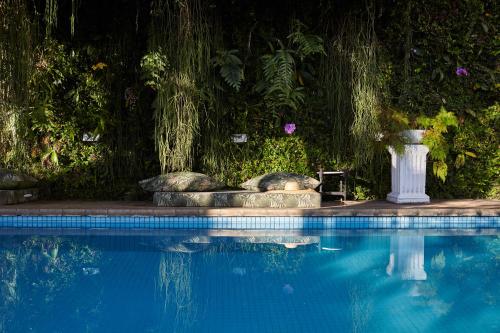 里约热内卢Mama Ruisa Boutique Hotel的一个带桌子和花瓶的游泳池
