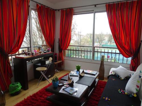 蒙鲁日La bambouseraie的客厅配有红色窗帘和桌子