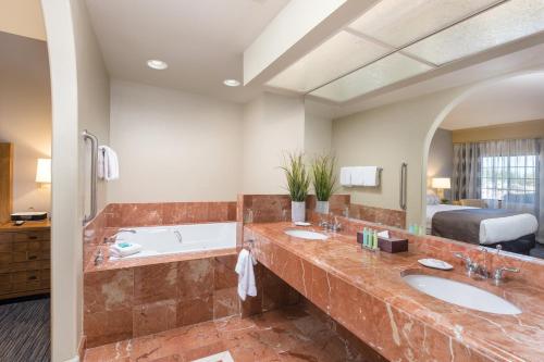 凤凰城莱格斯高尔夫度假酒店的一间带两个盥洗盆、一个浴缸和一张床的浴室
