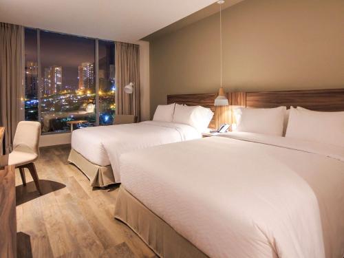 麦德林Novotel Medellin El Tesoro的酒店客房设有两张床和窗户。