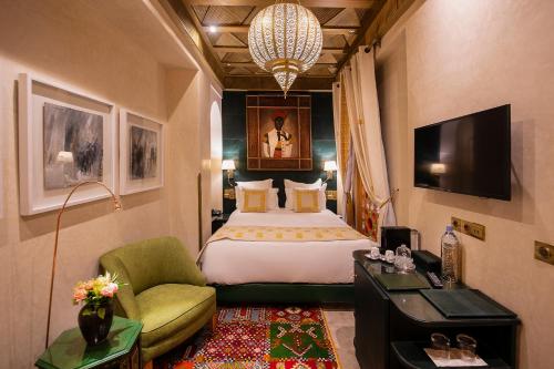 马拉喀什Elegancia Riad Boutique & SPA的酒店客房带一张大床和一把椅子