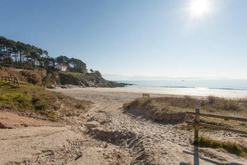 波多诺伏Chalet Arena de Canelas en 1ª línea de Playa, Sanxenxo的一条土路,通往带木栅栏的海滩