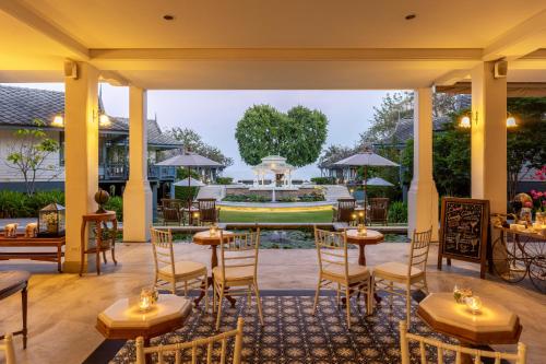 七岩Devasom Hua Hin Resort的庭院内的餐厅,配有桌椅