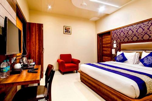 马图拉Hotel Spiti的一间卧室配有一张床、一张桌子和一把红色椅子