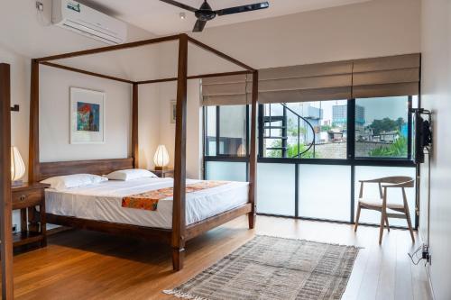 科伦坡Havelock Gardens BnB的一间卧室设有一张天蓬床和大窗户