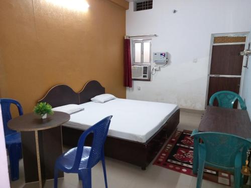 Kushinagarvindhyvasini guest house的配有一张床和一张桌子及椅子的房间