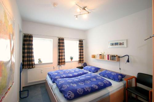 南赫夫特Gaestehaeuser-Heidehof-Wohnung-1的一间卧室配有一张带蓝色床单的床和一扇窗户。