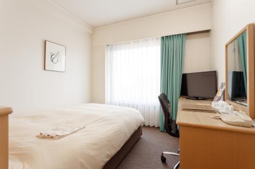 AkishimaAkishimaStationHotel TOKYO的酒店客房配有一张床和一张书桌及一台电视
