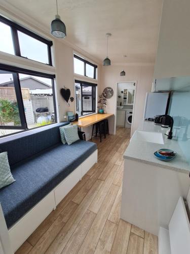 怀卡奈Aroha Tiny House Peka Peka的一间带蓝色沙发的客厅和一间厨房
