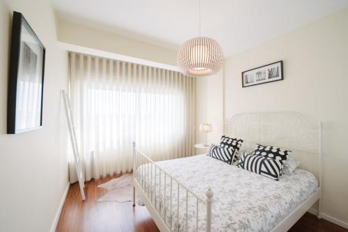 马托西纽什Apartamento Newark的白色卧室配有带黑白枕头的床