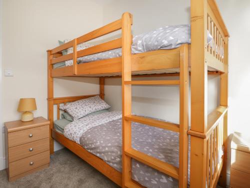 WigtonThe Croft Bungalow的一间卧室设有两张双层床和床头柜。