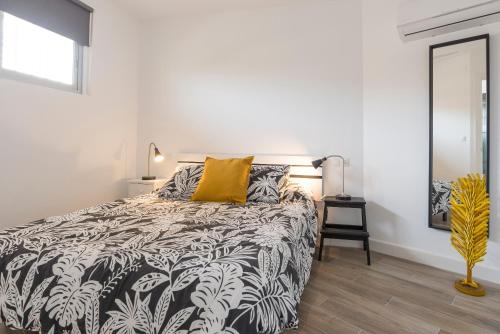 贝纳哈拉菲Paraiso del Sol II的卧室配有一张黑色和白色的床,配有黄色枕头