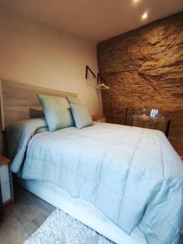 塞特尼尔Casa cueva La Tosca的卧室配有一张白色大床和砖墙