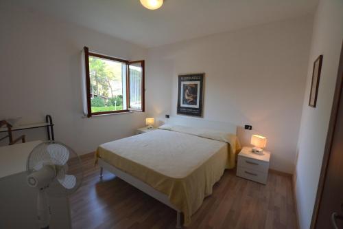 利尼亚诺萨比亚多罗Villa in Lignano Riviera comfortable的一间卧室设有一张床、一个窗口和风扇