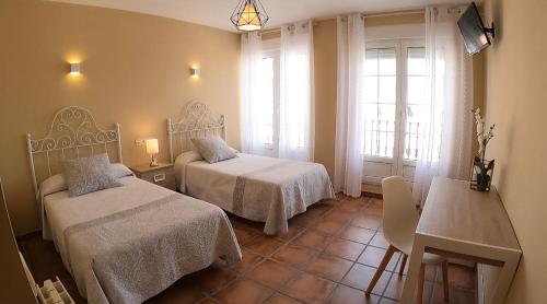 卡里翁德洛斯孔德斯Hostal Santiago的酒店客房设有两张床、一张桌子和一张桌子。