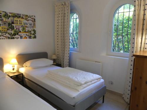 曼德琉-拉纳普勒Rez de jardin au calme et proche mer的一间卧室配有一张带白色床单的床和两个窗户。