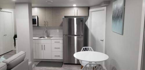 温尼伯Luxurious 2 bedroom basement suite的厨房配有不锈钢冰箱和桌子