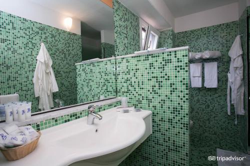 莱西纳Villaggio Albatros Resort的绿色瓷砖浴室设有水槽和镜子