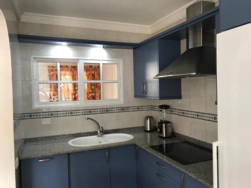 波多黎各Bungalow Isla Margarita的蓝色的厨房,配有水槽和窗户