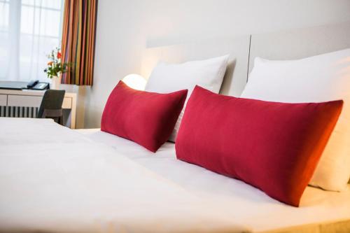 美因茨Erbacher Hof, Bistum Mainz的一张配有红色和橙色枕头的床