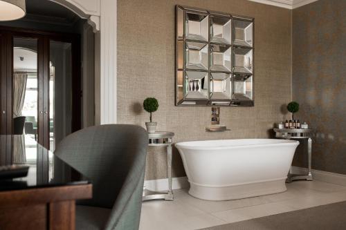 阿赛克兰拉尔德酒店的一间带大型白色浴缸和镜子的浴室