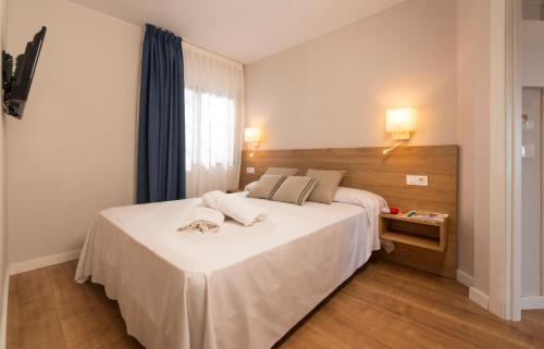 罗列特海岸Apartamentos Guitart的卧室设有一张白色大床和一扇窗户。